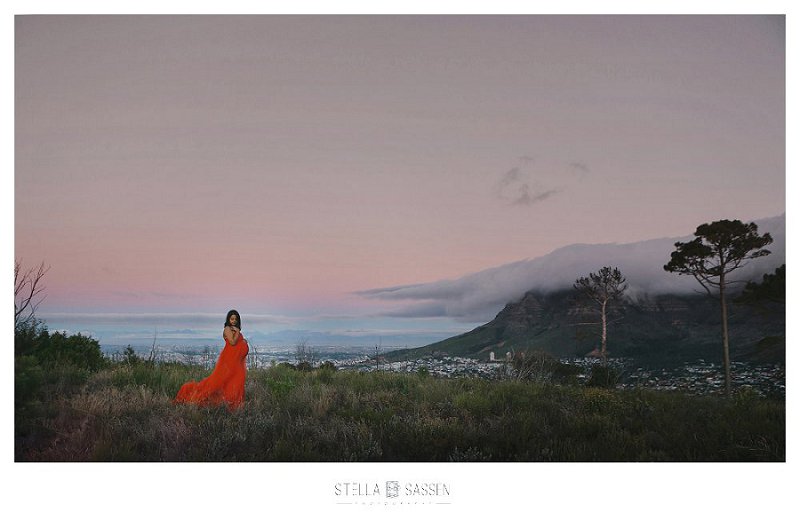 Maternity client in red dress on mountain at sunset