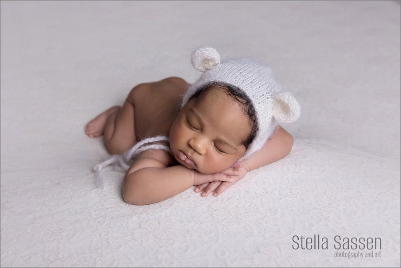 newborn photography of baby in little bear hat with props