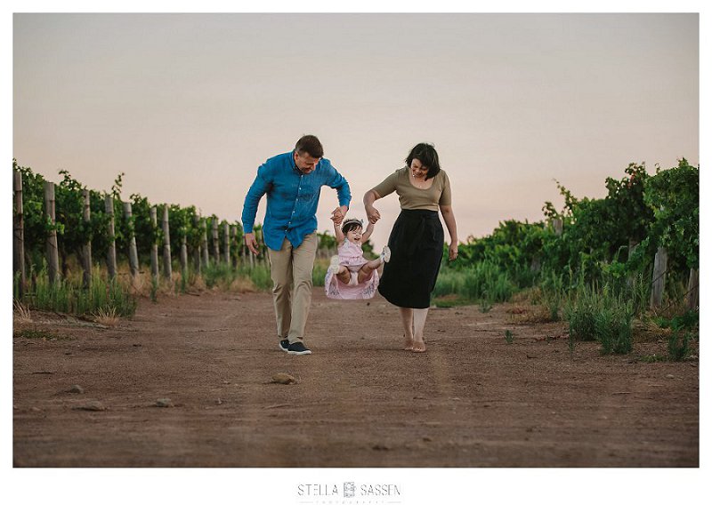 Family shoot toddler walking with parents on winefarm