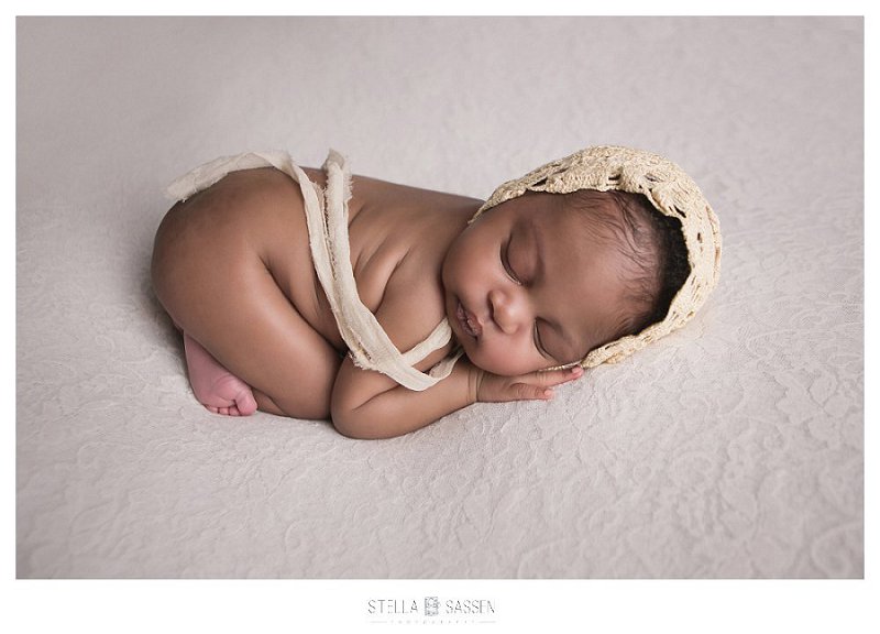 newborn baby with hat on lace background in photo shoot
