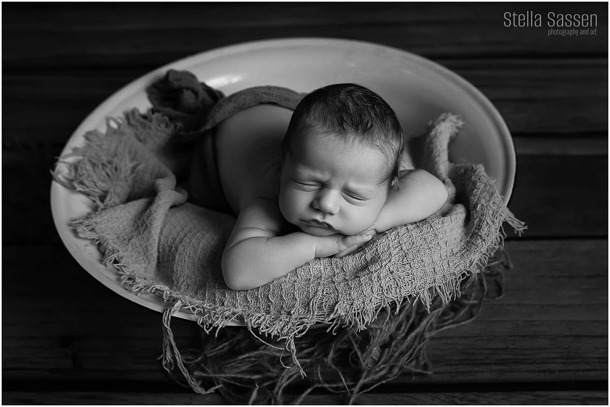 newborn baby boy sleeping in a old fashioned dish during a newborn shoot