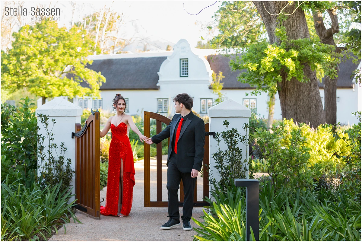 Matric Dance couple walking through a gate on a winefarm with their formal clothing